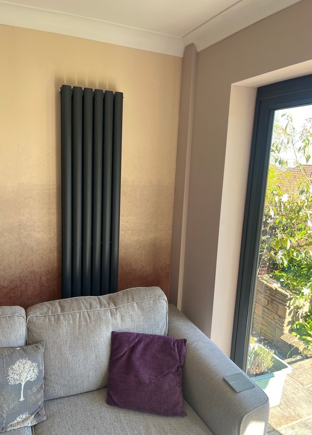 Tall anthracite radiator beside a living-room window