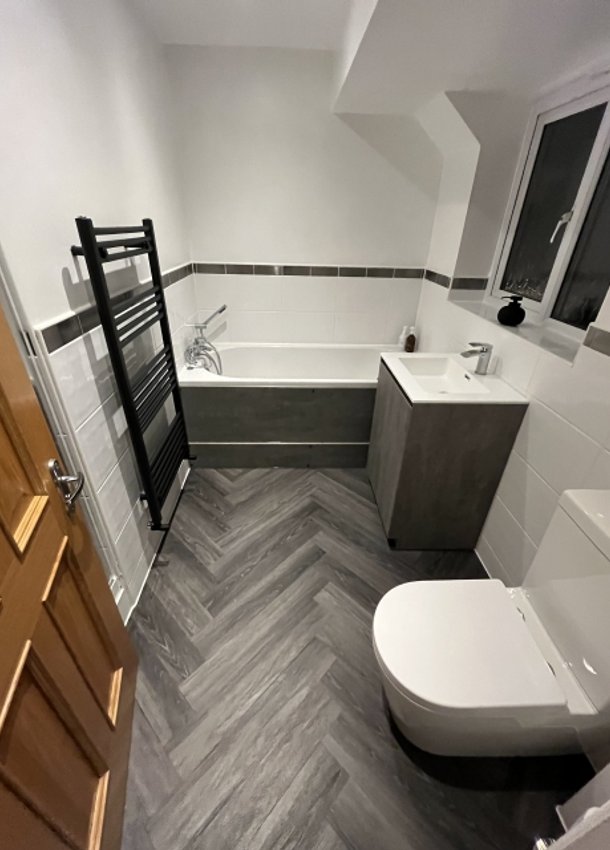 Bathroom with toilet, vanity unit, bath and black towel radiator