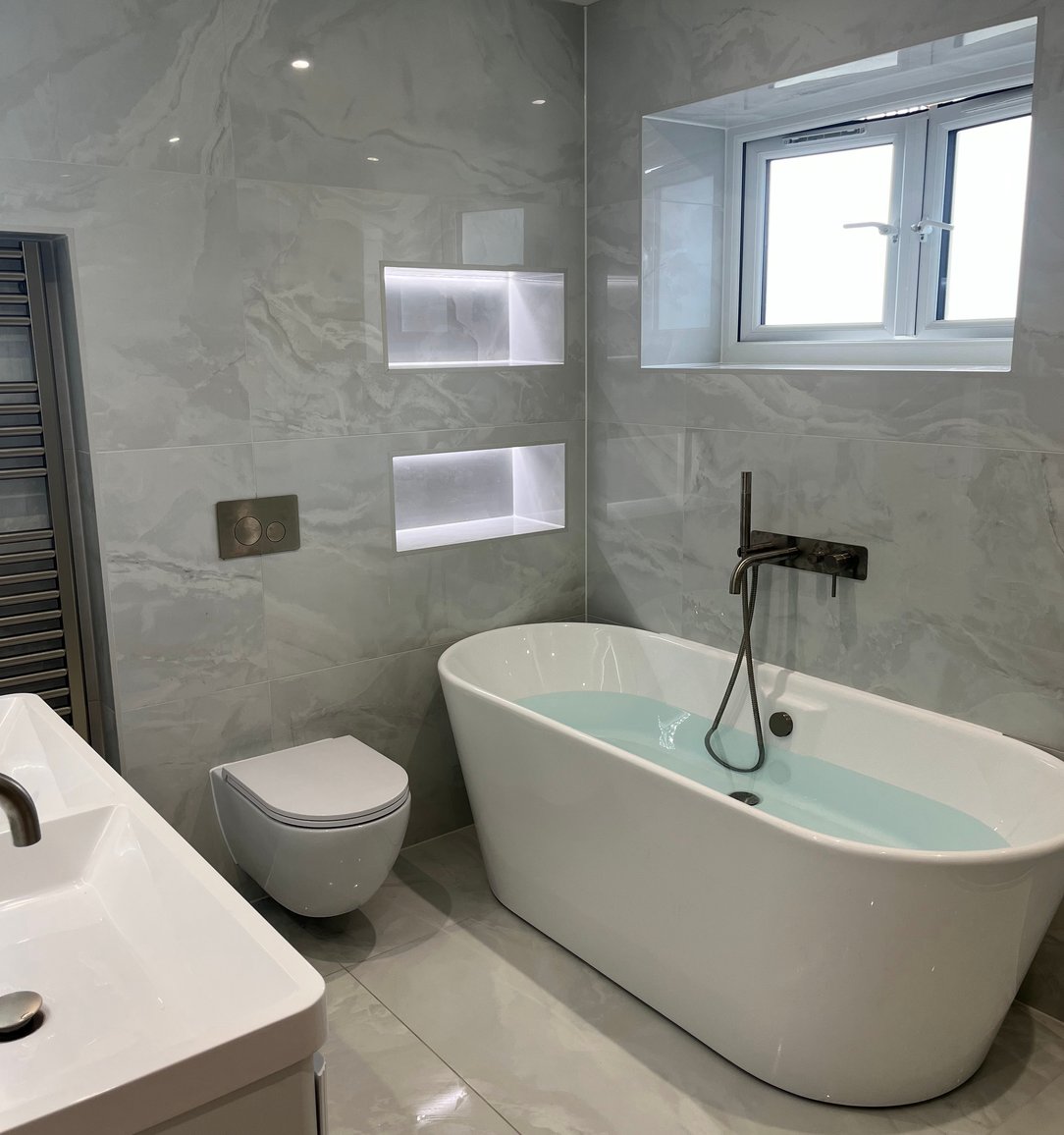 Grey bathroom with a freestanding bath and illuminated niches
