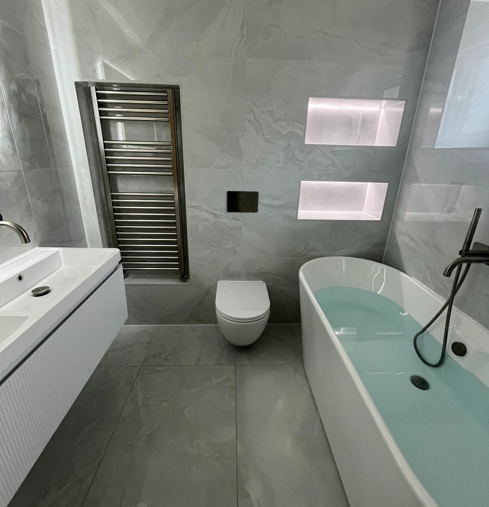 Grey bathroom with a vanity, wall-hung toilet and illuminated niches