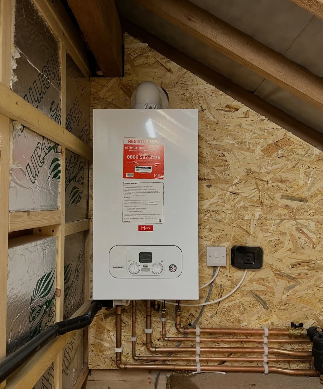 Boiler with copper pipework installed in a timber-framed loft space