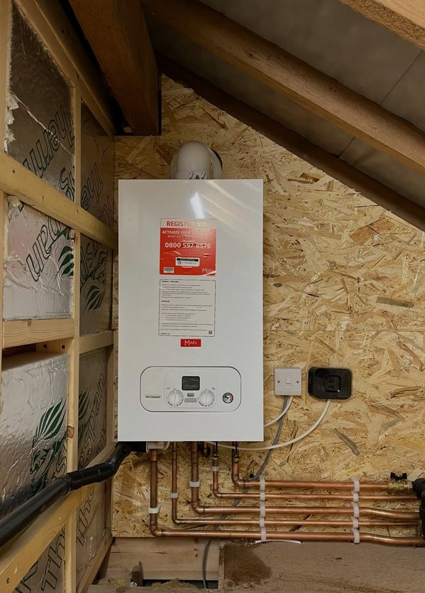 Boiler and copper pipework in a timber-framed loft space