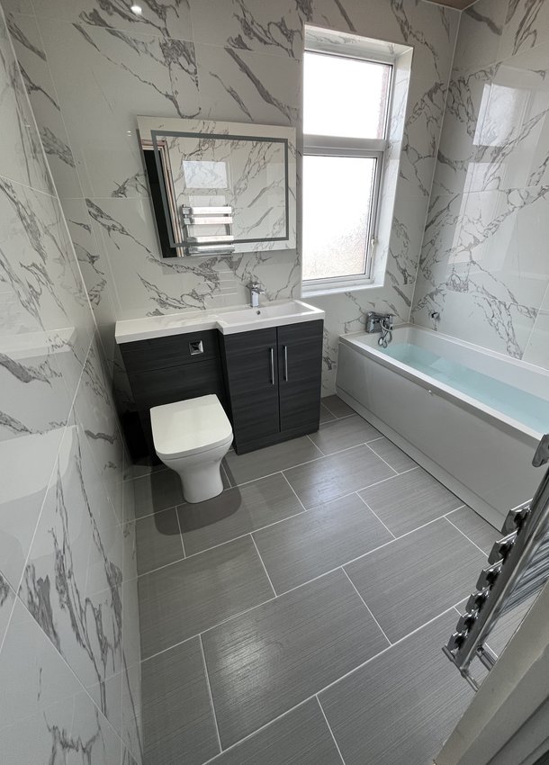 Marble-effect bathroom with black vanity, toilet and fitted bath