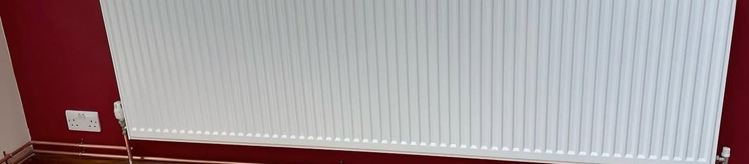 White panel radiator against a red wall