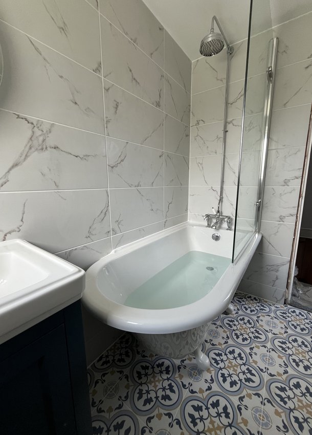 Bathroom with roll-top bath, rainfall shower and patterned floor tiles