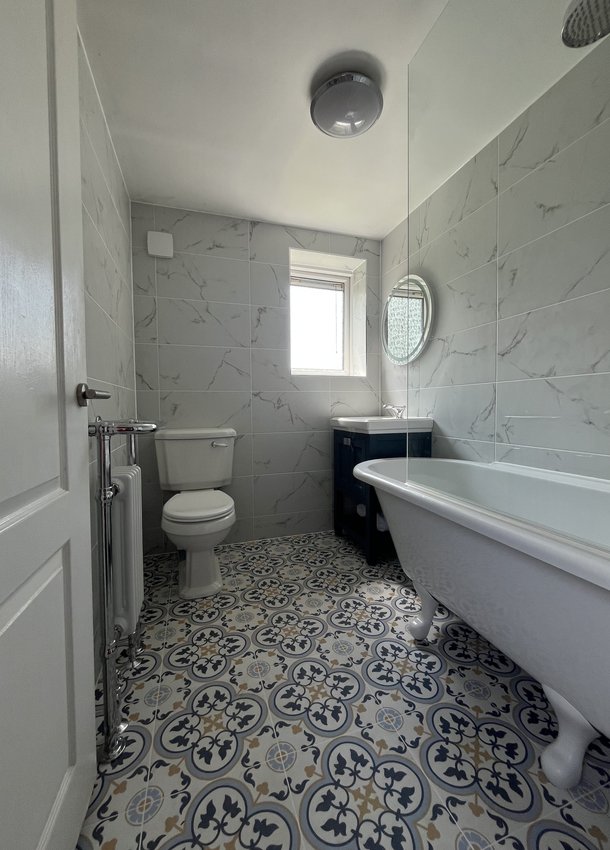 Bathroom with roll-top bath, toilet and patterned floor tiles