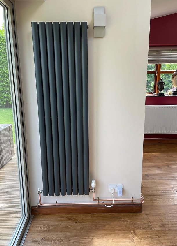 Vertical anthracite radiator beside patio doors