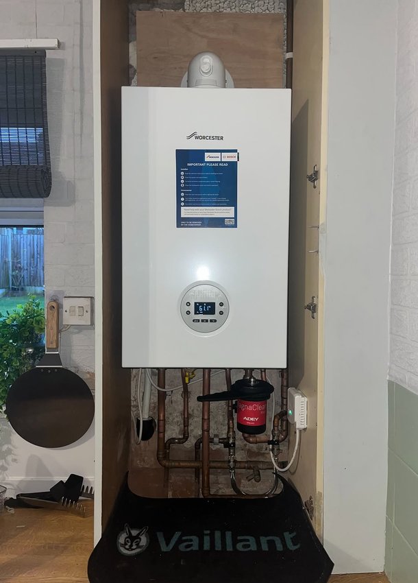 Wall-mounted boiler with control display and pipework below