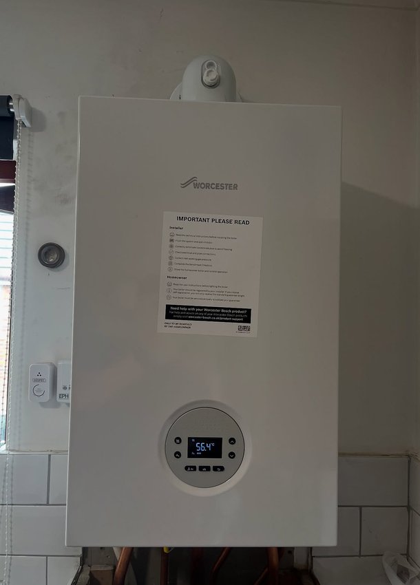 White wall-mounted boiler above a tiled splashback