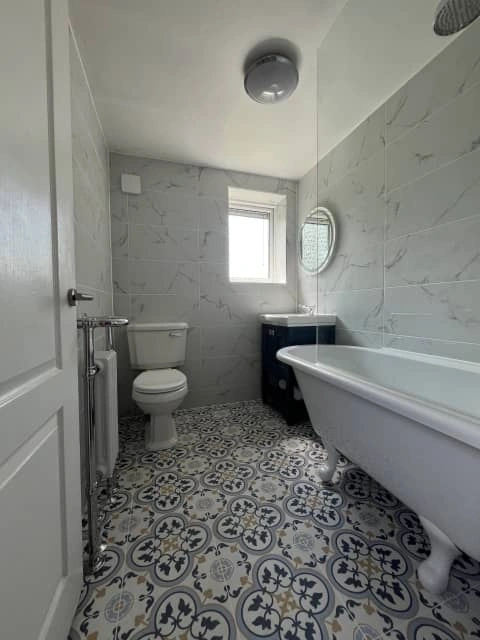 After: Contemporary bathroom with bathtub, tiled walls and chrome fittings