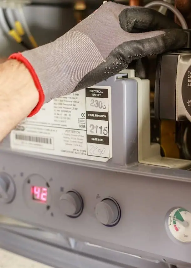 Plumber servicing the interior of a domestic gas boiler 