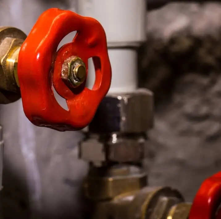 Close-up of red shut-off valve on residential plumbing system in Bolton